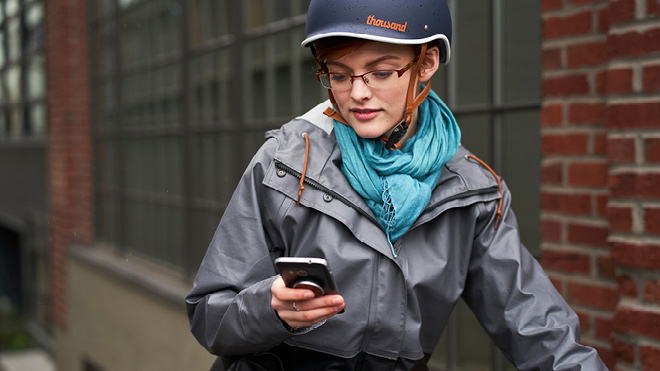 a woman wearing a helmet and a grey coat looking at her phone