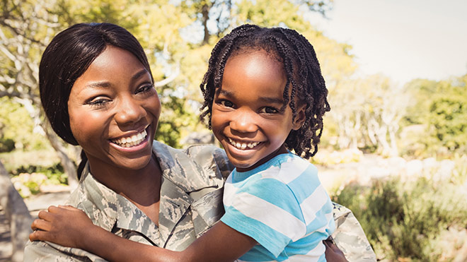 Smiling woman in military fatigues and her child.