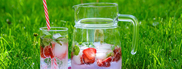 A glass and pitcher of refreshments on grass