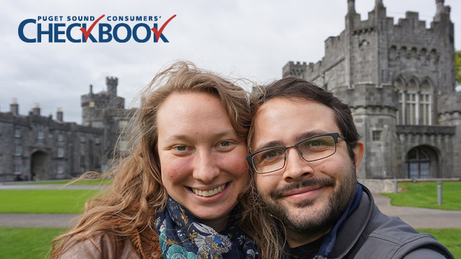 Couple huddled close together, smiling for the camera while situated in front of a medieval castle. Consumers' Checkbook logo in top left corner.