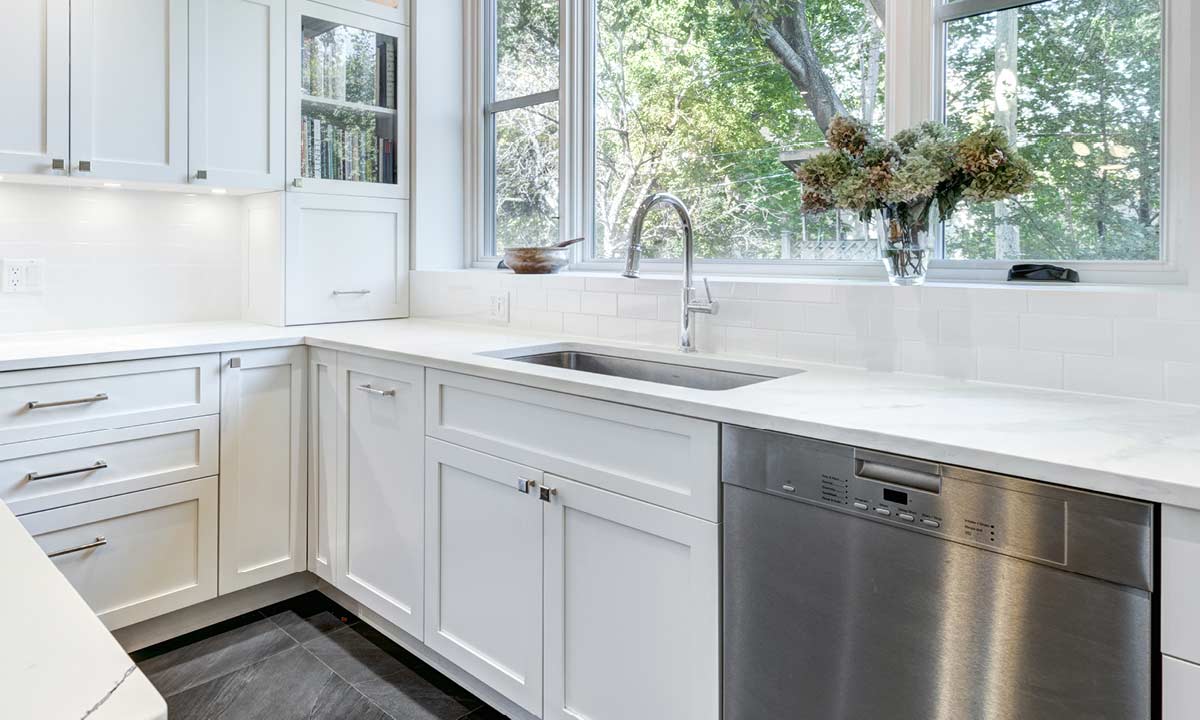 Photo of a kitchen with white Shaker-style cabinets and a dishwasher with a stainless steel door.