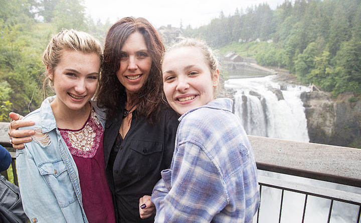 A woman and two teen girls pose for a picture with Snoqualmie Falls in the background.